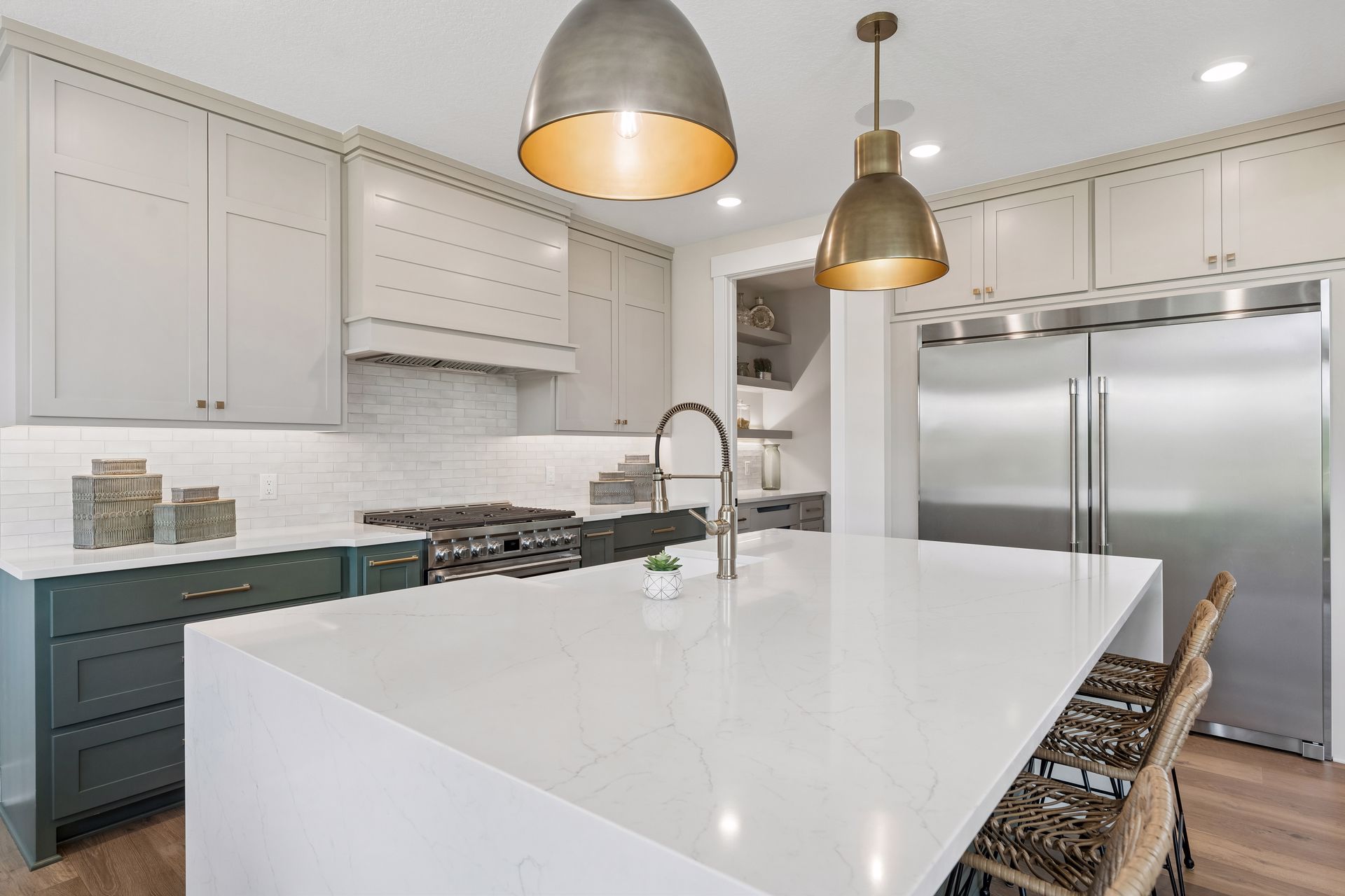 Quartz waterfall island with designer pendant lighting and professional appliances